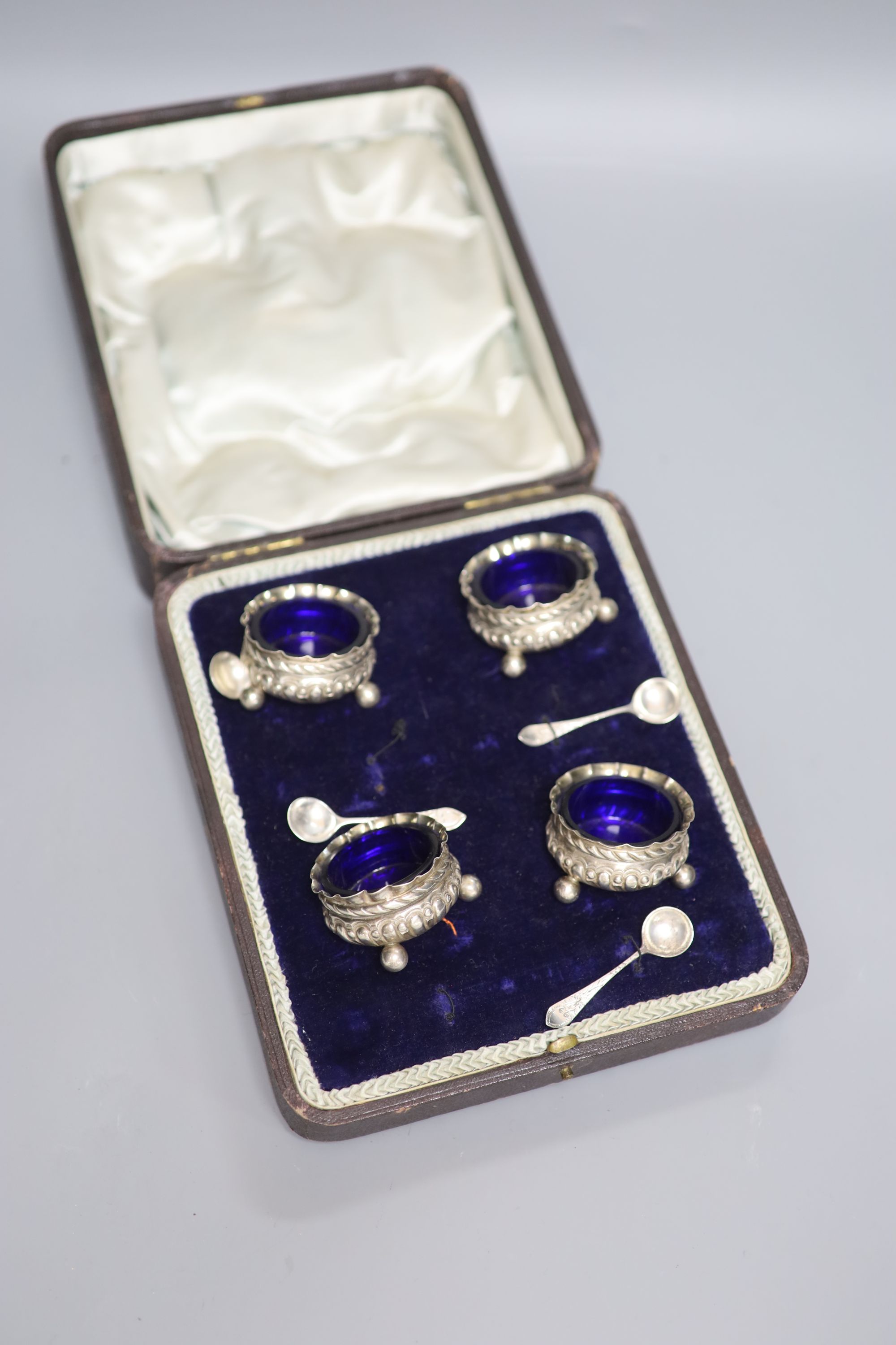A cased set of four Victorian repousse silver salts, Matthew John Jessop, Birmingham, 1887, 5cm, and four associated spoons.